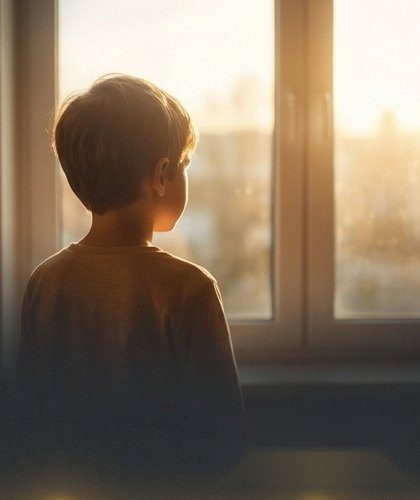 Kind am Fenster im Abendlicht